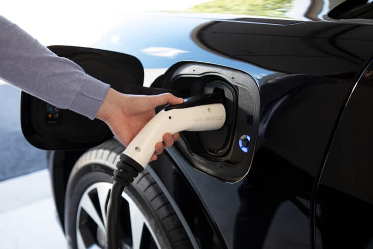 Person plugging EV charger into electric car.